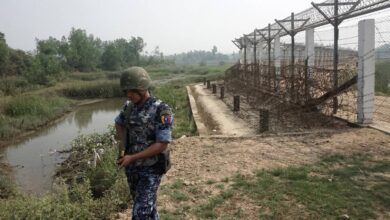 An armed Myanmar border guard police patrols the barbed wire fence along the Bangladesh border in Maungdaw District, Rakhine State, on March 18, 2018 (Joe Freeman / AFP)