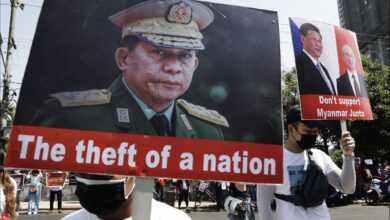 Protesters hold placards depicting Sen-Gen Min Aung Hlaing during an anti-coup demonstration in Yangon in February 2021 (EPA)