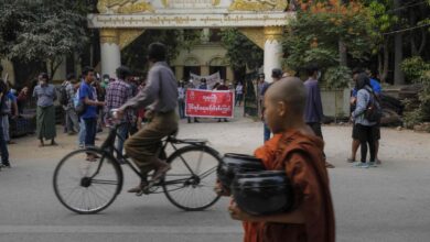 A child novice walks by a group of protesters in Mandalay on April 6, 2021. (Photo: AFP)