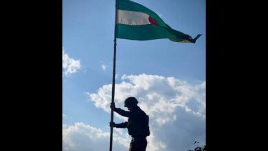 A Ta'ang National Liberation Army soldier raises the group’s flag after a successful mission during Operation 1027, a large offensive in northern Shan State, Myanmar in late 2023. (Photo: Ta'ang National Liberation Army)