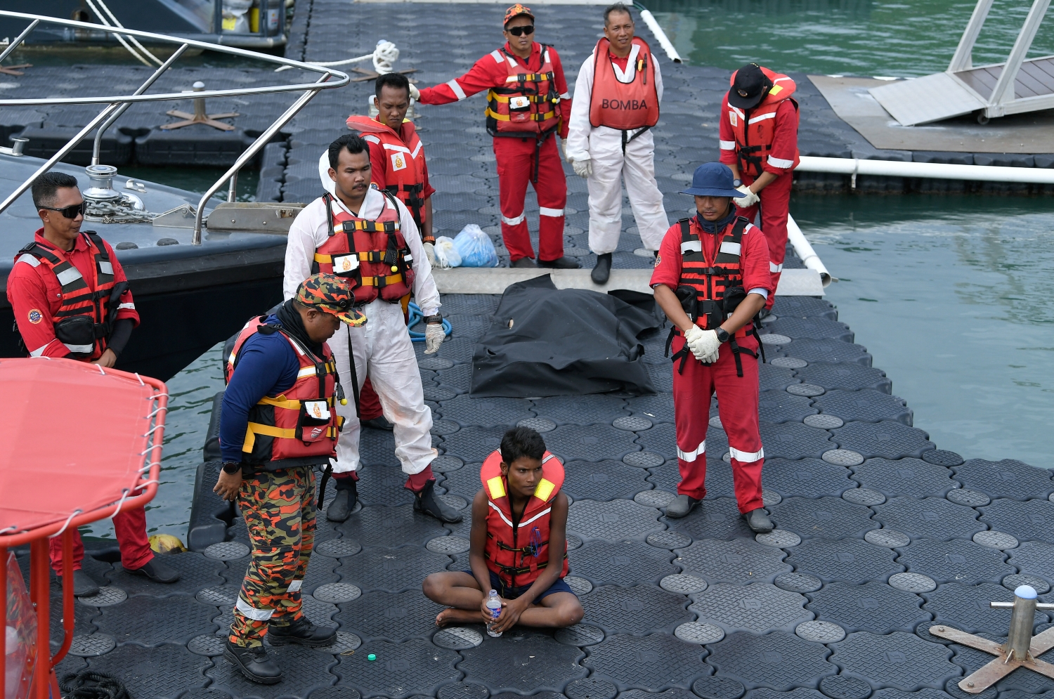 Rohingya migrant Iman Shorif, centre, is surrounded by rescue workers on November 11, days after the boat he was on capsized off the coast of Malaysia (Photo: Hakim Mustapha / AFP)
