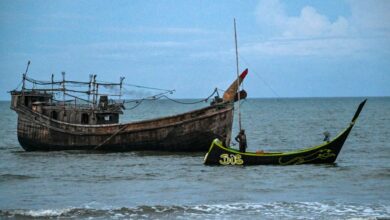 A fisherman’s boat sits next a boat used by Rohingya refugees who arrived in Indonesia’s Aceh Province in November 2023 (Chaideer Mahyuddin / AFP)