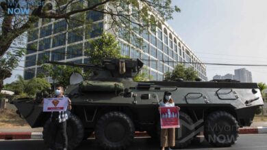 Anti-coup protesters hold up signs in front of the Central Bank of Myanmar’s Yangon office in February 2021 (Photo: Myanmar Now)