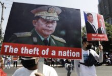Protesters hold placards depicting Min Aung Hlaing during an anti-coup demonstration in Yangon in February 2021 (EPA)