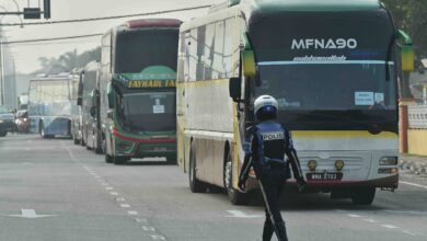 A policeman walks in front of buses carrying Myanmar nationals being returned from Malaysia to Myanmar on the outskirts of Kuala Lumpur on September 29, 2026 (Arif Kartono/AFP)