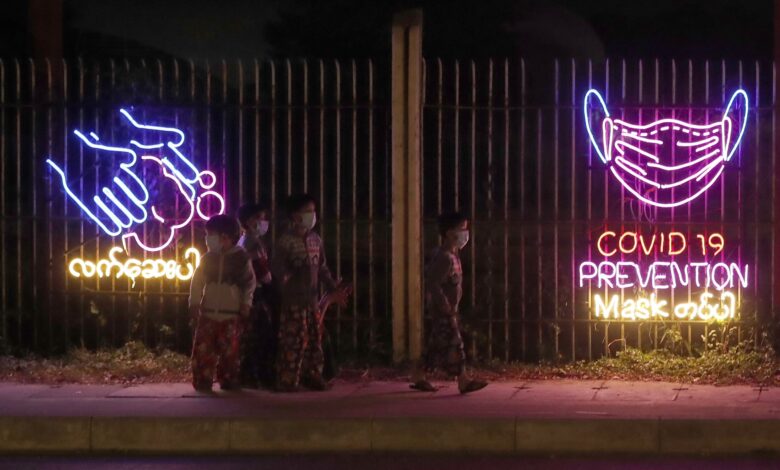 ကိုဗစ်ရောဂါကာကွယ်ရန် လက်ဆေး၊ နှာခေါင်းစည်းတပ်ကြရန် ရန်ကုန်မြို့ တစ်နေရာတွင် ၂၀၂၀ ဒီဇင်ဘာလအတွင်းက အသိပေးထားစဉ်။ (ဓာတ်ပုံ − EPA)