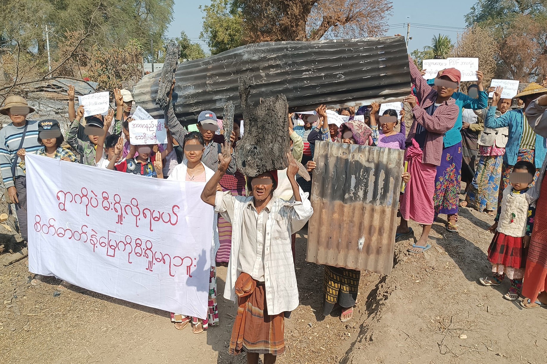 စစ်ကိုင်းတိုင်း၊ ပုလဲမြို့နယ်အတွင်း နေအိမ်များ မီးရှို့ဖျက်ဆီးခံရပြီးနောက် နေစရာအိမ်မရှိတော့သည့် အညာသားများက စစ်အာဏာရှင်အလိုမရှိကြောင်း ငြိမ်းချမ်းစွာ ချီတက်ဆန္ဒပြ တောင်းဆိုခဲ့ကြသည်ကို ၂၀၂၂ ခုနှစ် ဖေဖော်ဝါရီလက တွေ့ရစဉ်။ (ဓာတ်ပုံ- ပုလဲလူထုသပိတ်တိုက်ပွဲဦးဆောင်ကော်မတီ)