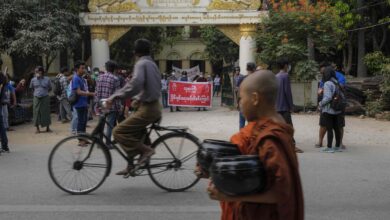 ၂၀၂၁ ခုနှစ် ဧပြီလ ၆ ရက်နေ့က မန္တလေးမြို့တွင် ဆန္ဒပြနေသူများအနီး ကိုရင်ငယ်တစ်ပါး ဖြတ်လျှောက်သွားစဉ်။ (ဓာတ်ပုံ-AFP)