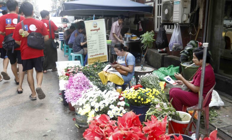 ရန်ကုန်မြို့ ဈေးတစ်နေရာအတွင်း ရွေးကောက်ပွဲ လက်ကမ်းစာစောင် ဖြန့်ဝေနေသူ အချို့ကို တွေ့ရပုံ (ဓာတ်ပုံ − EPA)