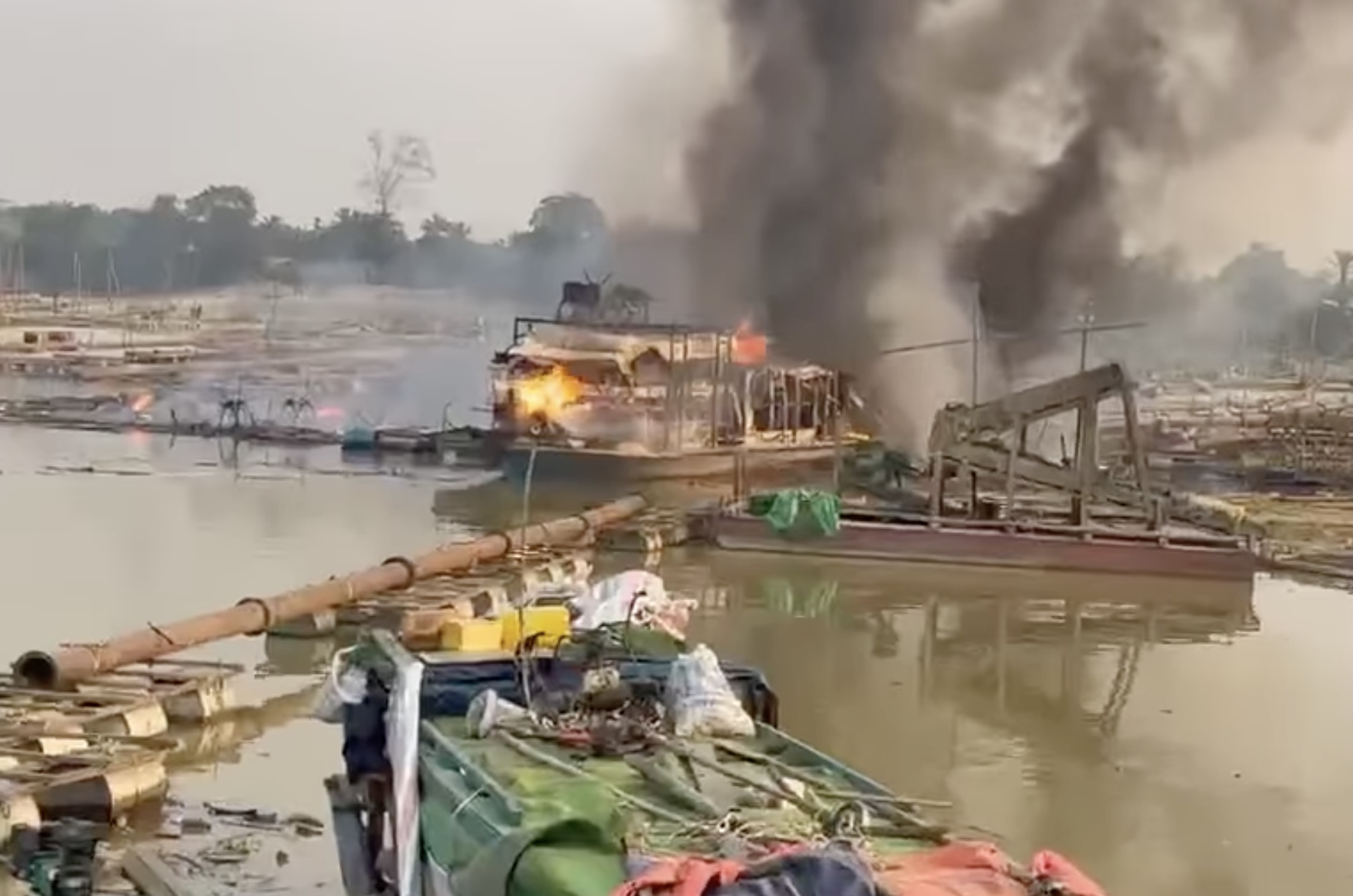 မတ်လ ၁၀ ရက်နေ့က လေကြောင်းတိုက်ခိုက်မှုကြောင့် စင်းခန်းကျေးရွာအနီး ရွှေမျှောလုပ်သည့် စက်လှေတစ်စီး မီးလောင်နေစဉ်။ (ဓာတ်ပုံ- Screengrab)