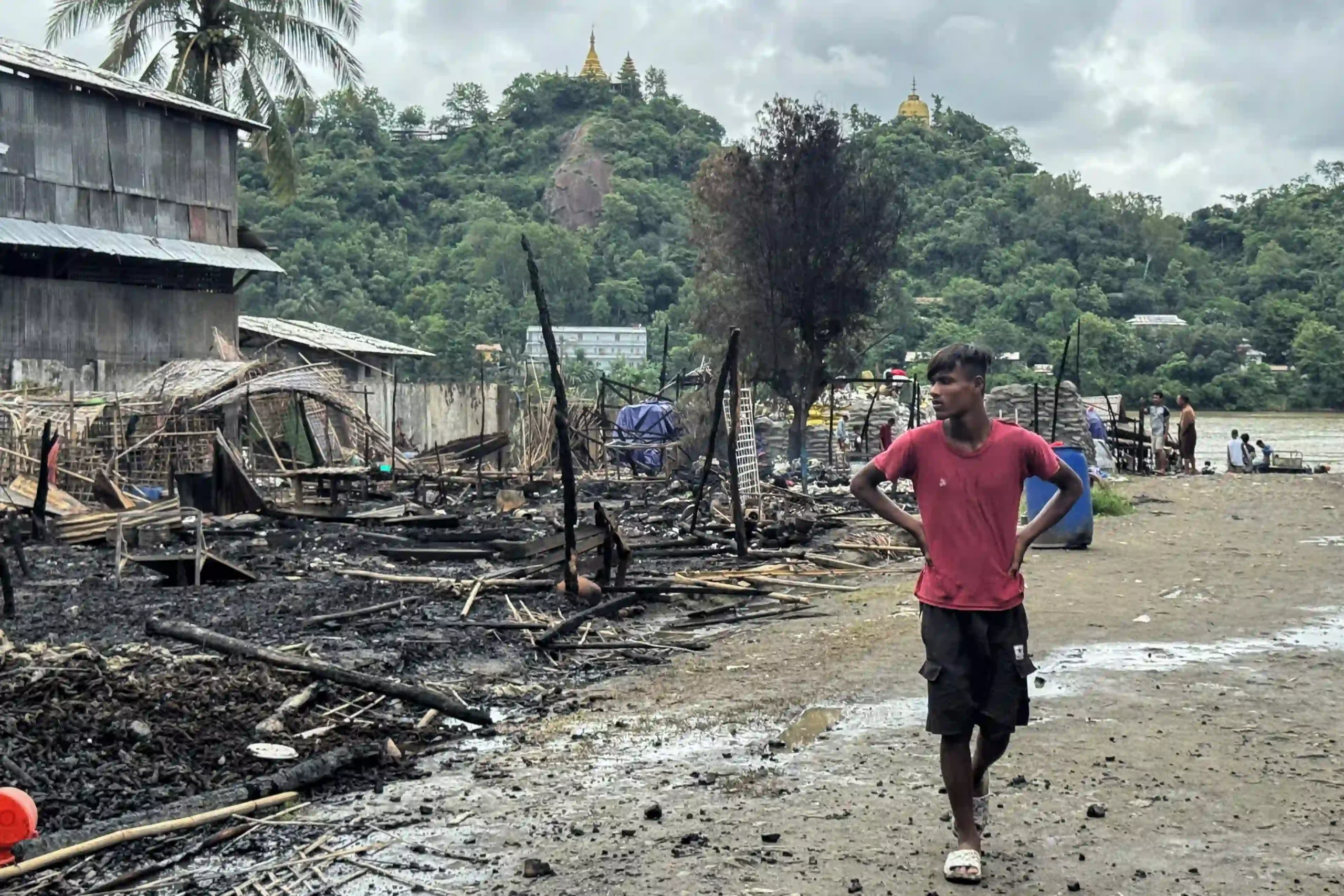 ဇွန်လ ၁၈ ရက်က ရခိုင်ပြည်နယ်အနောက်ပိုင်း ကျောက်တော်မြို့တွင် ဗုံးကြဲခံရပြီးနောက် အပျက်အစီးများအနီး တွေ့ရသော အမျိုးသားတစ်ဦး။  (ဓာတ်ပုံ- AFP) 