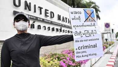 အာဏာသိမ်းစစ်ခေါင်းဆောင် ဦးမင်းအောင်လှိုင်ကို ကန့်ကွက်ဆန္ဒပြကြောင်း ပိုစတာ ကိုင်ထားသူ တစ်ဦးကို ဘန်ကောက်မြို့၊ UN ရုံးရှေ့၌ တွေ့ရစဉ်။ (ဓာတ်ပုံ-AFP)